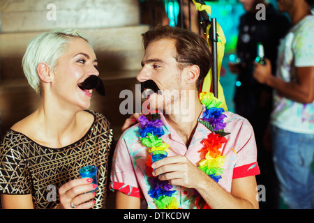 Couple wearing fake moustaches at party Banque D'Images