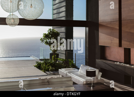 Des canapés et des tables in modern living room overlooking ocean Banque D'Images