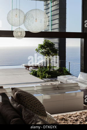 Des canapés et des tables in modern living room overlooking ocean Banque D'Images