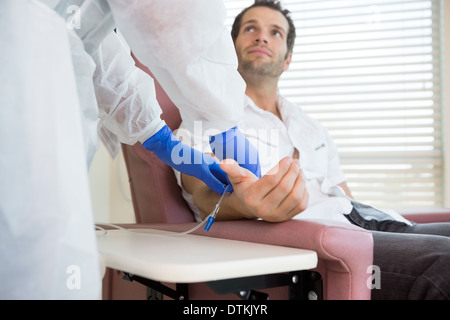 À la recherche infirmière au patient tout en recevant un traitement intraveineux JE Banque D'Images