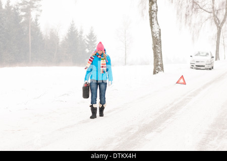 Femme transportant du gaz peut neige panne de voiture Banque D'Images