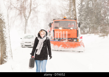 Femme marche avec du gaz peut voiture d'hiver Banque D'Images