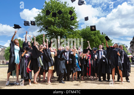 Célébrer les diplômés de leur diplôme en jetant leurs conseils de mortier dans l'air sur College Green, Bristol. Banque D'Images