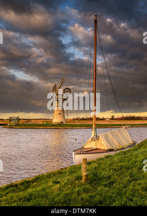 Thurne Mill et bateau à voile sur les Norfolk Broads, East Anglia sous un ciel d'hiver moody Banque D'Images