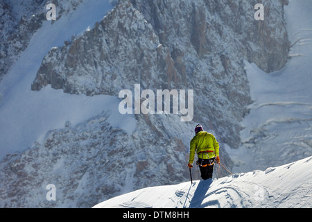 Traversée d'un grimpeur solitaire au-dessous de la crête du Mont Blanc, haut au-dessus de la vallée de Chamonix dans les Alpes françaises. Banque D'Images