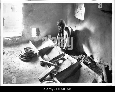 Jeune femme indienne Hopi pour la farine de maïs de meulage, ca.1900 Banque D'Images