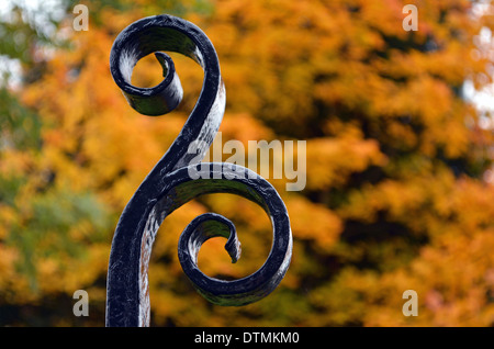 Détail de l'entrée du parc en fer forgé avec les arbres d'automne en arrière-plan. Banque D'Images