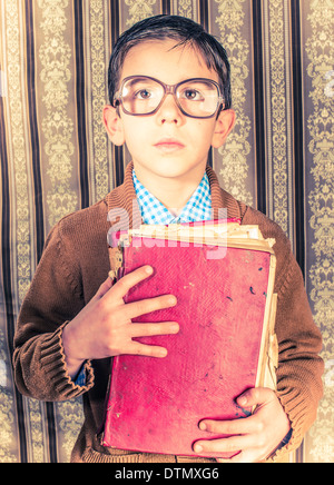 Enfant avec des lunettes vintage rouge attente livre. Vêtements vintage Banque D'Images