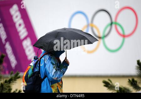 Sochi, Russie. Feb 21, 2014. Un bénévole promenades dans la pluie passé les anneaux olympiques à Sotchi les Jeux Olympiques de 2014 à la Pierre Saint Martin, près de Sotchi, Russie, le 21 février 2014. Photo : Kay Nietfeld/dpa/Alamy Live News Banque D'Images