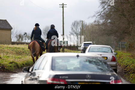 UK, Gloucestershire : Automobile tourisme lentement devant les chevaux de les enfourcher le long d'une route de campagne dans le Gloucestershire. Banque D'Images