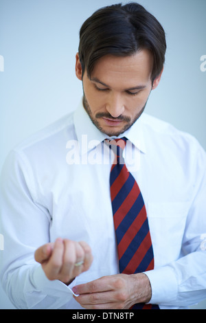 Jeune homme attrayant faisant ses poignets chemise Banque D'Images