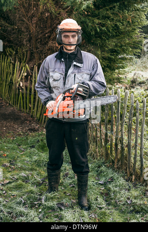 Portrait de jardinier professionnel avec tronçonneuse debout dans le jardin. Banque D'Images