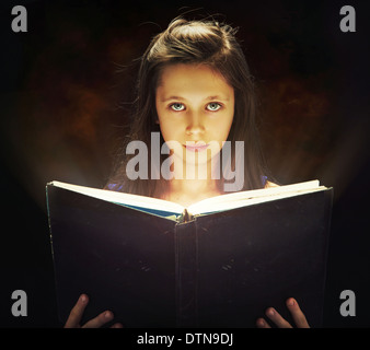 Jolie fille de l'ouverture du livre de magie Banque D'Images