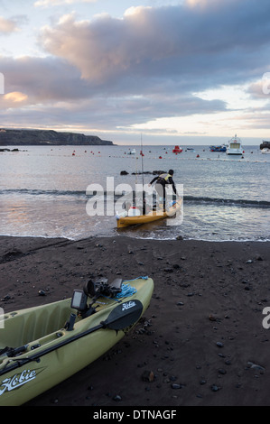 Deux hommes avec des kayaks de pêche de sortir tôt le matin à partir de la plage de San Juan, Tenerife, Canaries, Espagne. Banque D'Images