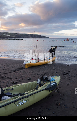 Deux hommes avec des kayaks de pêche de sortir tôt le matin à partir de la plage de San Juan, Tenerife, Canaries, Espagne. Banque D'Images