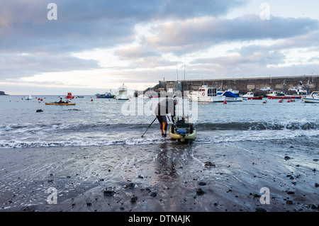 Deux hommes avec des kayaks de pêche de sortir tôt le matin à partir de la plage de San Juan, Tenerife, Canaries, Espagne. Banque D'Images