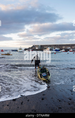 Deux hommes avec des kayaks de pêche de sortir tôt le matin à partir de la plage de San Juan, Tenerife, Canaries, Espagne. Banque D'Images