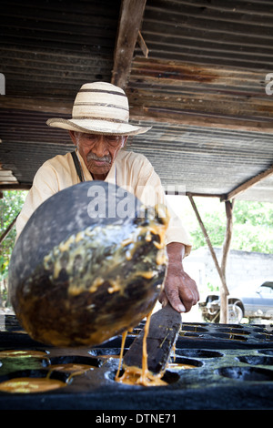 Verser le jus chaud homme panaméen à partir de la canne à faire Raspadura, près de Penonome, Province de Cocle, République du Panama. Banque D'Images
