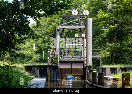 Jeune homme de verrouillage s'ouvre pour les touristes dans un kayak dans un canal dans la réserve de biosphère de Spreewald, Brandebourg, Allemagne Banque D'Images