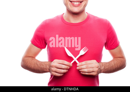Smiling handsome guy holding fourchette en plastique et le couteau près de son estomac sur fond blanc. studio shot. Banque D'Images