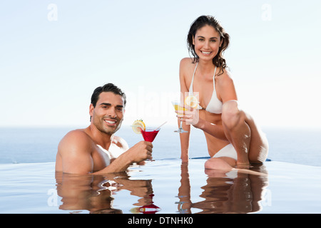 Cheerful couple having cocktails dans la piscine Banque D'Images