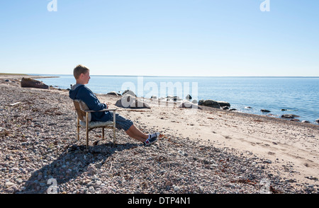 L'homme des jeunes adultes se détendre et de s'asseoir sur le banc près de la mer et les regarder à distance. Banque D'Images