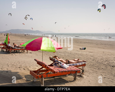 L'Inde, Goa, Morjim, femme en train de bronzer sur une chaise longue tout en kitesurf profiter du vent Banque D'Images