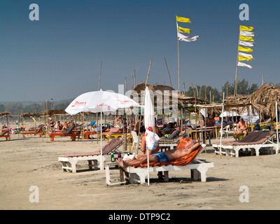 L'Inde, Goa, Morjim, touristes bronzer sur les chaises longues Banque D'Images