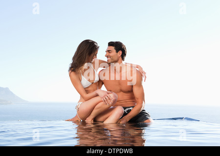 Couple sitting on pool edge ensemble Banque D'Images