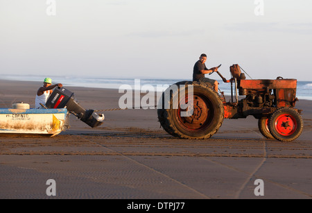 Faites glisser les pêcheurs d'un bateau à l'eau avec un tracteur sur la plage de la côte du Pacifique à Mechapa, Nicaragua Banque D'Images