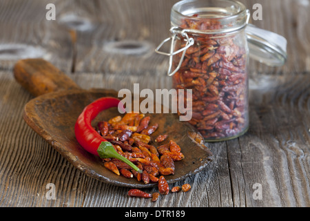 Piment rouge sur une pelle en bois avec des piments séchés d'un pot de rangement avec copie espace dans la zone supérieure gauche de l'image ​​The Banque D'Images