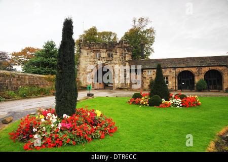 Historique une porterie avec pelouse et plantes à fleurs rouges (géraniums). Banque D'Images