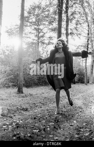 Modèle de mode des années 60 avec manteau de fourrure en marche en forêt France Europe Banque D'Images