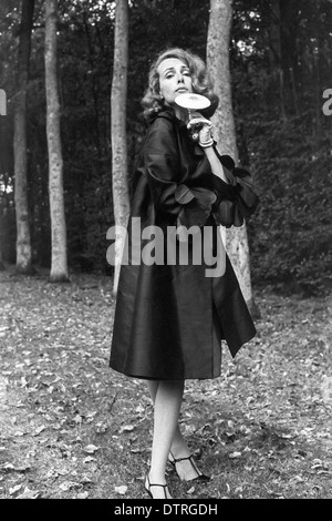 Modèle de mode des années 60 avec manteau noir et champignons posing in forest Banque D'Images