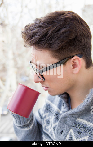 Jeune homme avec des lunettes de boire du café en plein air Banque D'Images