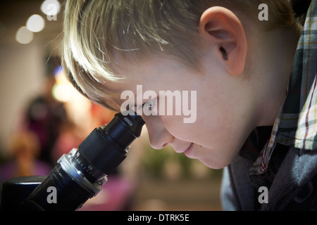 Portrait d'enfant Boy looking through microscope dans laboratoire d'école Banque D'Images