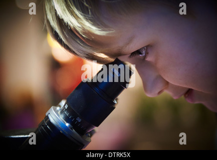 Portrait d'enfant Boy looking through microscope dans laboratoire d'école Banque D'Images