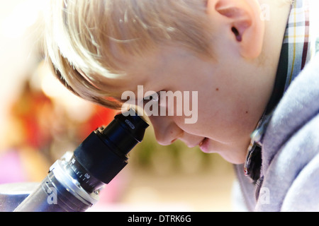 Portrait d'enfant Boy looking through microscope dans laboratoire d'école Banque D'Images