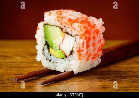 Californie uramaki sushi roll closeup détail sur baguettes Banque D'Images