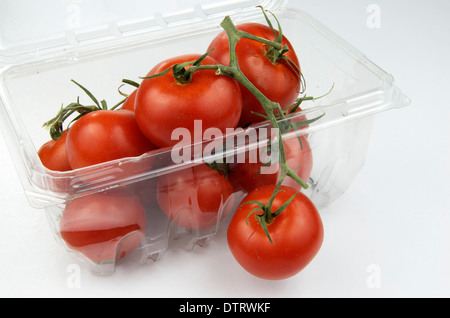 Les tomates mûries sur vigne dans un récipient en plastique à partir de l'épicerie. Banque D'Images