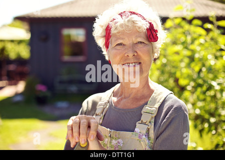 Closeup portrait of senior woman standing in backyard garden Banque D'Images