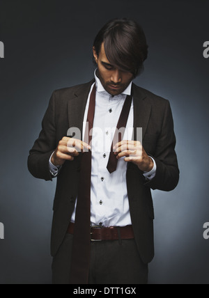 Image en fonction de porter une cravate. Beau mannequin en train de s'habiller sur fond noir Banque D'Images