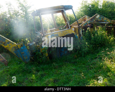 Old rusty tracteur lentement obtenir couvert dans un sous-bois Banque D'Images