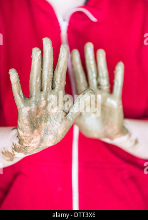 Mains boueuses de femme travaillant avec la poterie. De près de l'argile recouverte de palmiers. Banque D'Images