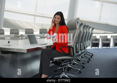 Mixed Race woman on cell phone in conference room Banque D'Images