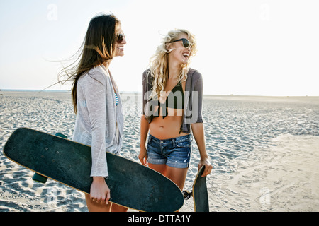 Les femmes avec des planches à roulettes standing on beach Banque D'Images