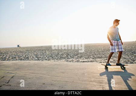 Caucasian man skating on beach