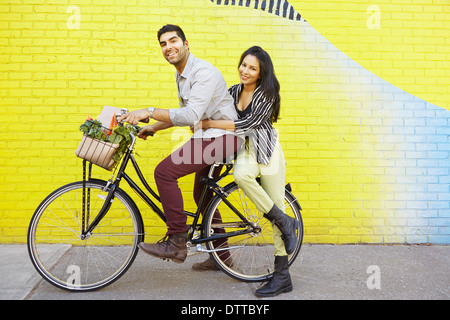 Indian couple riding bicycle on city street Banque D'Images