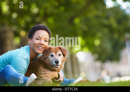 Black woman petting dog in park Banque D'Images