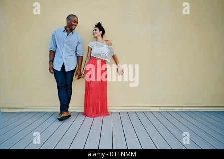 Couple standing against wall outdoors Banque D'Images